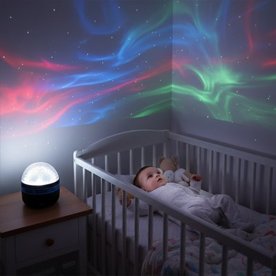 Veilleuse projection sur table avec bébé dans son lit qui regarde le plafond