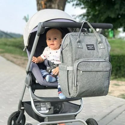 Sac a langer gris attaché à une poussette et bébé qui sourit