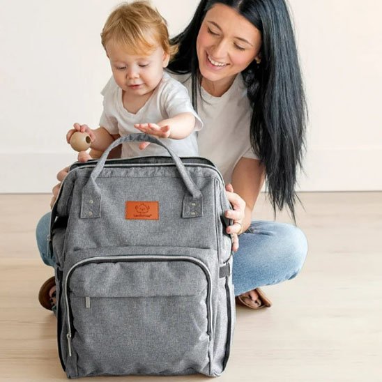 Sac a langer gris pale avec maman et bébé qui tient le sac