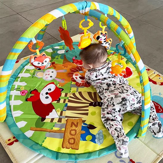 tapis d'éveil bleu, vert et jaune avec bébé sur le ventre
