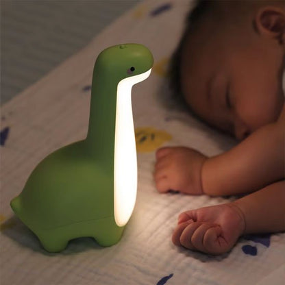 Veilleuse bébé dinosaure verte dans le lit avec bébé