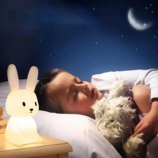 Veilleuse bébé lapin sur table avec enfant qui dort dans son lit
